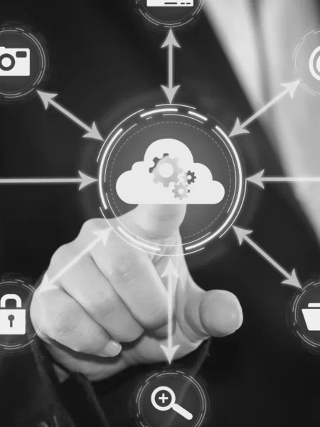 A person in a suit points to a cloud icon on a virtual interface with several other icons connected by arrows, symbolizing tasks and functions related to cloud computing and data management.