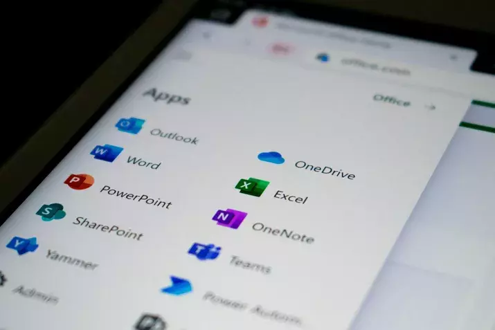 A close-up photo of a screen showing a list of Microsoft 365 services, showing Office app icons, including Outlook, Word, PowerPoint, SharePoint, Yammer, OneDrive, Excel, OneNote, Teams, and Power Automate. The screen is part of a web browser window showcasing the Microsoft 365 suite.