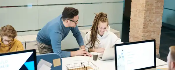 Man teaching woman on laptop showing her how to be savvy with human risk management