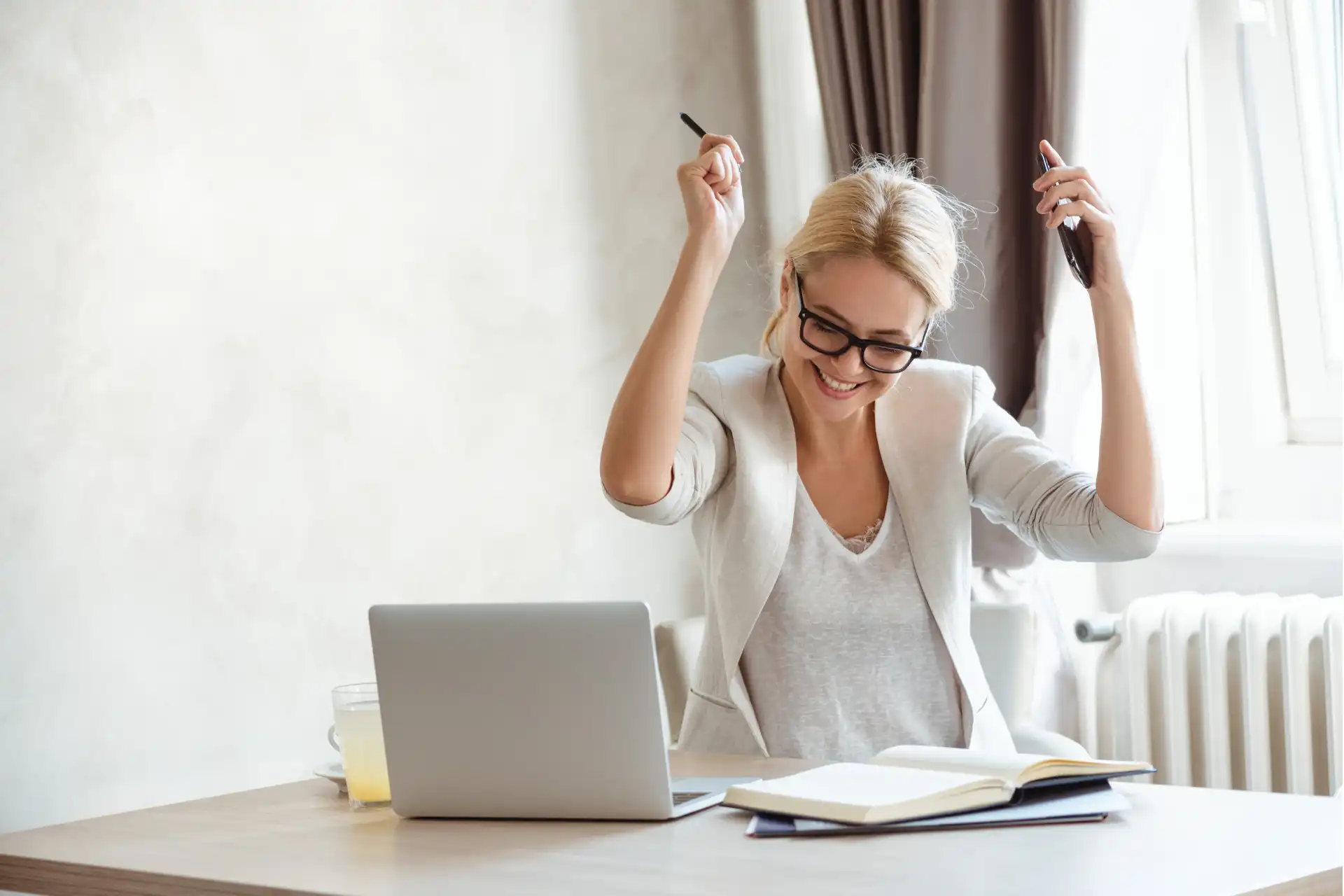 Woman celebrating success while using an all-in-one business system on a laptop.